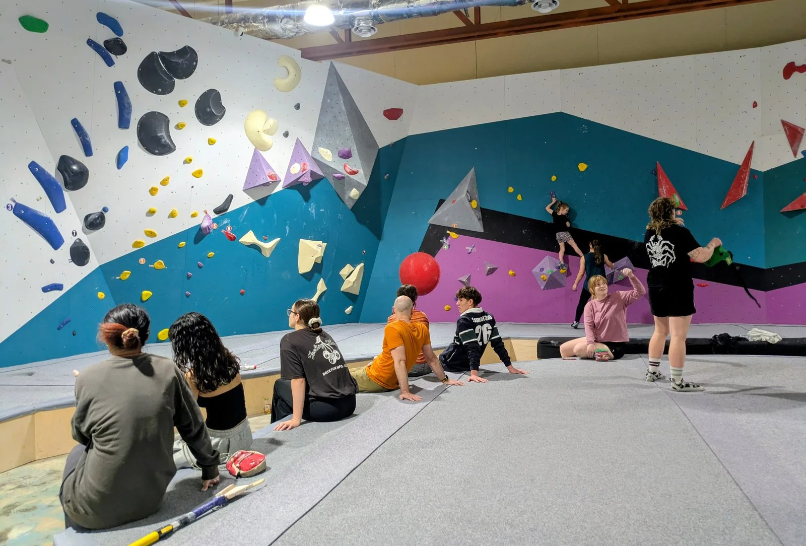 A group session at GRIPswich — climbers watching from the mats while others work a problem